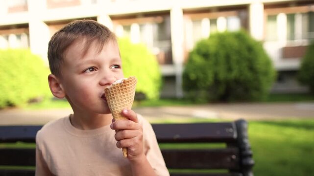 Serious boy eats milk flavored ice cream with chocolate coated waffle cone during summer cold. Frozen dessert may soothe swollen throat while child grimaces.