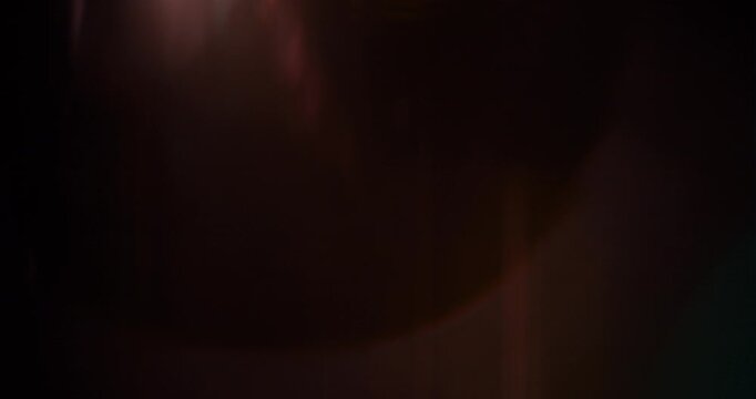 Slow motion of lens flare isolated on black background. Anamorphic lens. Cinematic glowing light overlay with optical streaks and rays for VFX compositing and transitions.
