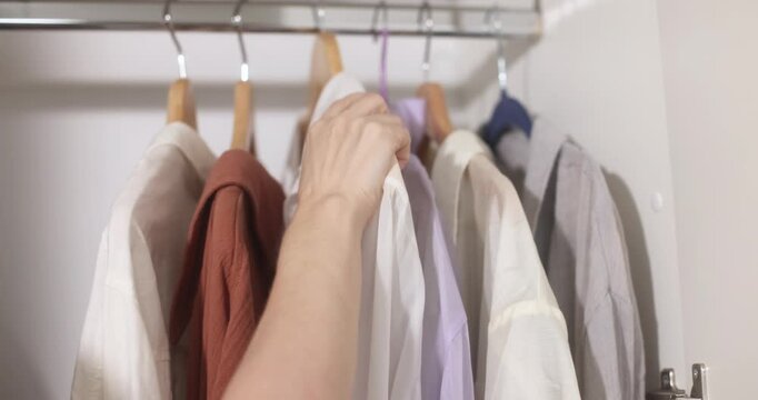 Clothing items hanging on a rack with wooden hangers, apparel display.
