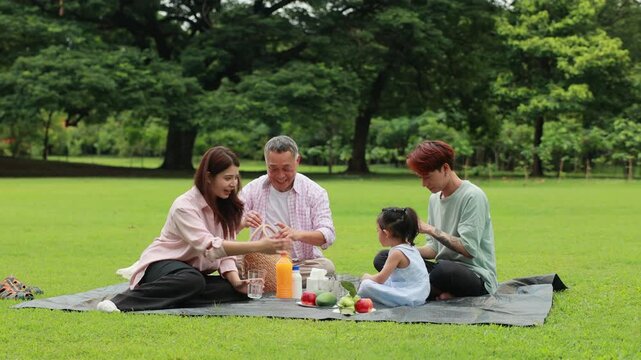 food and drinks. Happy Asian family having fun time on picnic at city nature park, outdoor activitie