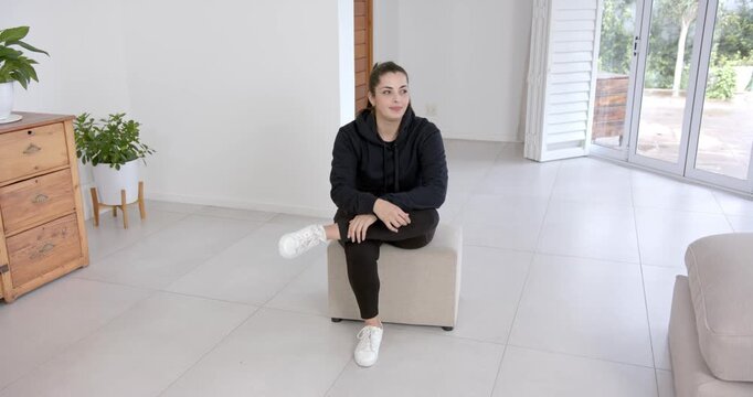 High speed photography for dynamic scenes, sitting on ottoman, woman in casual wear looking away tho
