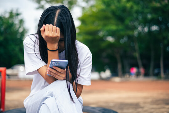 anxious worried teen girl with her smartphone as a conceptual backdrop for cyberbullying social media trauma, teenager mental health crisis, depression and panic attack