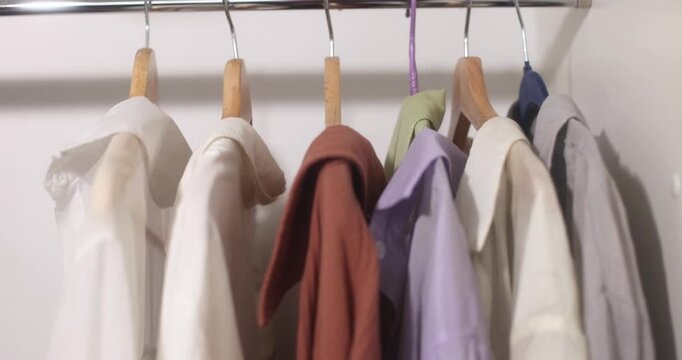 Clothing items hanging on a rack with wooden hangers, apparel display.
