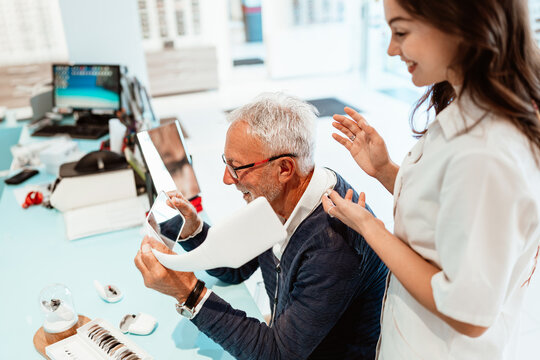 Medical specialist adjusting a sound amplification device for an elderly man during a professional consultation in a modern healthcare facility, focusing on wellness and hearing health.