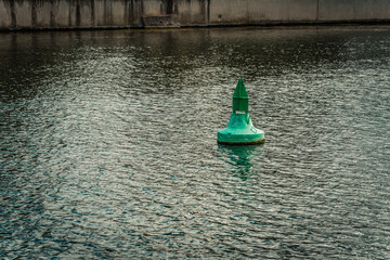 Green buoy floating in water near a concrete wall during daytime © funkenzauber