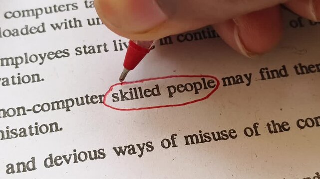 Closeup of hand with red ink pen mark circle around to emphasize or highlight Skilled People word on news paper article page. Unemployment, labour shortage, recession and worker crisis news concept.