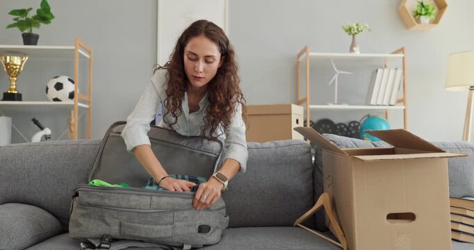 Young woman prepares clothes and luggage at home before starting college and moving away. She is getting ready for a new chapter. Student packs personal items for dorm living and campus life.