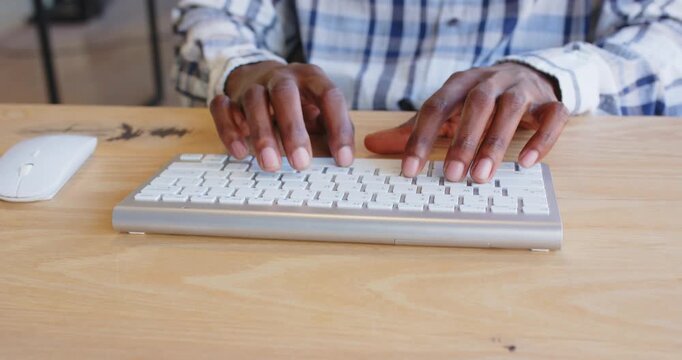 Hands typing on keyboard and using mouse at office desk, focusing on work