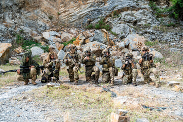 Obraz premium Military personnel train in rocky terrain during an exercise in an outdoor setting with various tactical equipment