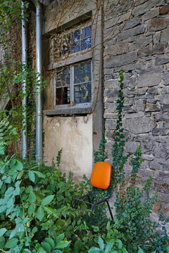 Alter Stuhl an einer &uuml;berwucherten Hauswand mit Fenster