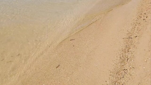 Calming sea waves. Surface and texture of pristine blue turquoise sea water during a hot summer day. Sand, beach, shore, costline