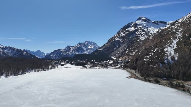 alpine village sils maria frozen silsersee shoreline road engadin valley switzerland mountain peaks larch forest winter aerial panorama drone flight