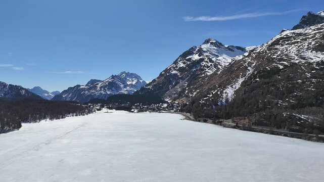 sils maria hamlet lakeside frozen silsersee shoreline road engadin valley switzerland snowcapped peaks larch forest winter panorama drone aerial flight