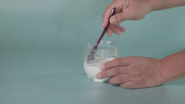 Milk and yogurt being stirred with a spoon