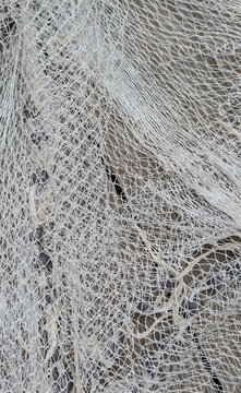 Close-up texture of a white woven fishing net with lead weights