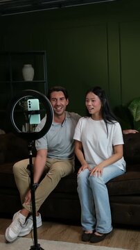Content creators talking to the camera on a smartphone while sitting on a couch at home