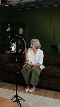 Older woman talking and gesturing while recording a video for her social media channel at home