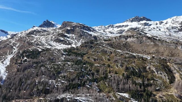 snow dusted jagged peaks alpine ridge larch forest slope rocky scree swiss alps switzerland graubunden engadin valley wilderness winter drone aerial view