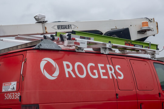 Calgary, Alberta, Canada. September 18, 2026. A close-up view of a red Rogers utility service van with a ladder and boom lift on the roof.