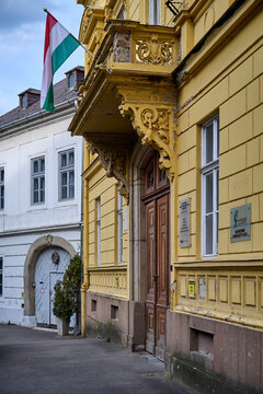 Historic yellow building decorated with a Hungarian flag along a quiet street in Eger, Hungary