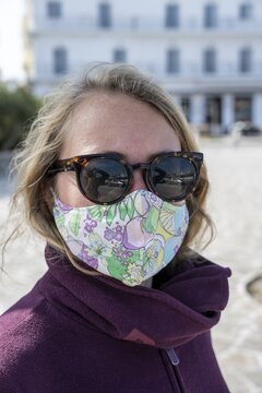 Young woman on vacation with mouth to nose covering, mask vs corona, greece