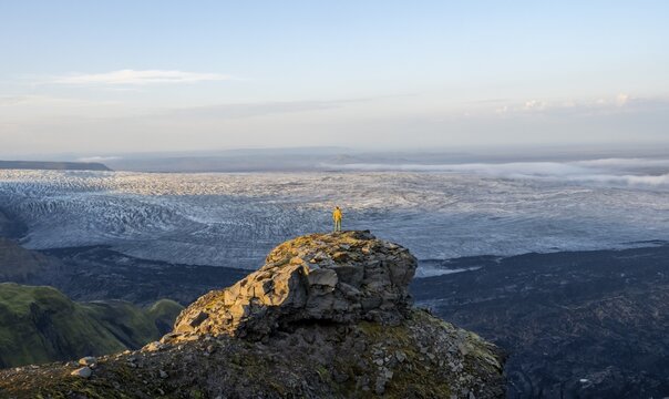 Young man, tourist in front of impressive glacier, in the evening light, Impressive landscape with mountains and glacier, glacier tongues K&ouml;tluj&ouml;kull, Myrdalsj&ouml;kull glacier Pakgil, Iceland
