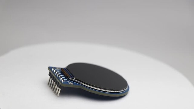Round display module lying flat rotating slowly on white background