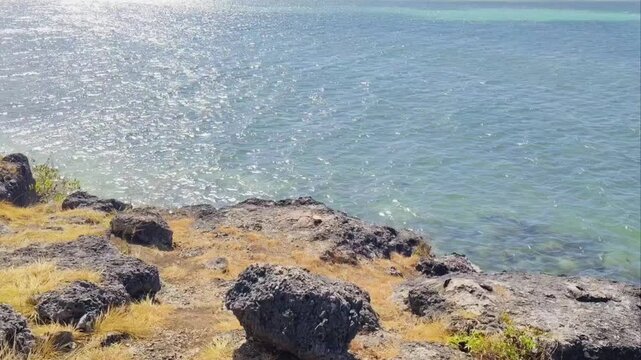 Calming sea waves. Surface and texture of pristine blue turquoise sea water during a hot summer day. Sand, beach, shore, costline