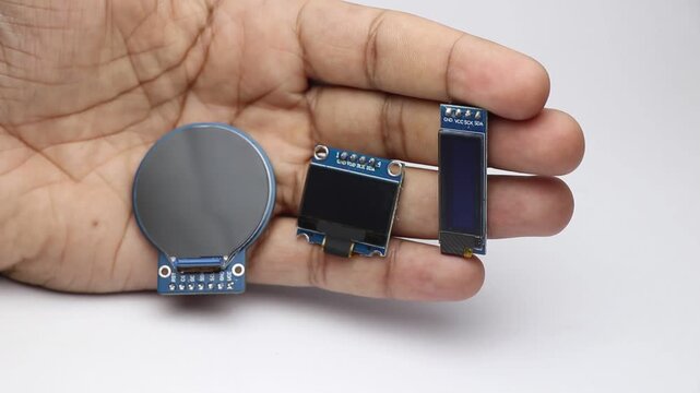 Hand holding round and rectangular oled display modules for electronics projects