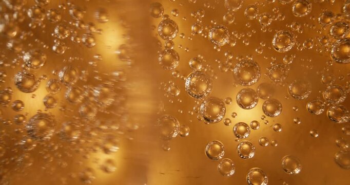 Slow motion bubbles rising through amber liquid inside glass beer bottle in macro close up gentle upward drift with subtle pan tracking movement, probe view.
