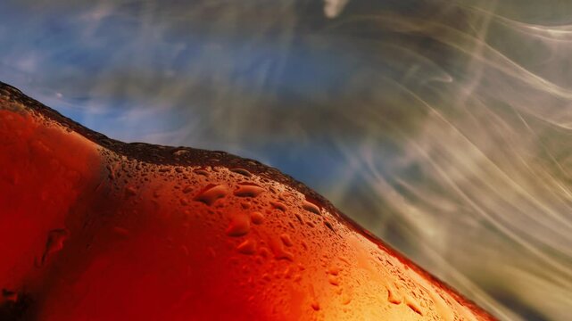 Slow motion closeup of amber beer drink in frosted glass with rising vapor and condensation on tabletop.