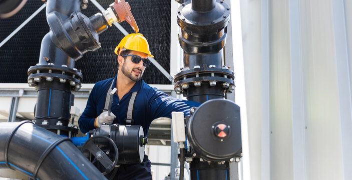 Engineer in hard hat inspecting industrial valves and pipelines, technician checking mechanical pipe system and equipment in a factory, worker monitoring water treatment plant and control valves