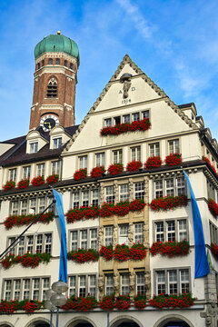 Traditional Bavarian Architecture with Red Geraniums and Frauenkirche Tower in Munich, Germany