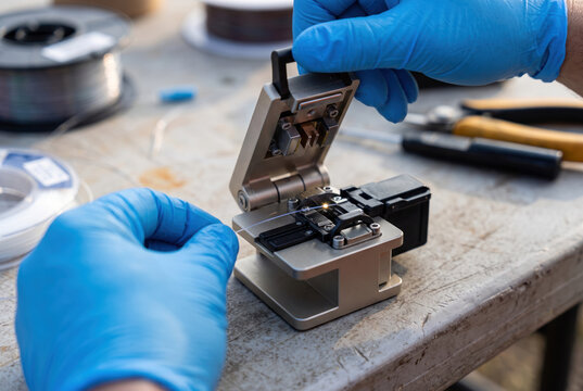 Fiber optic splicer with blue gloves on laboratory workbench.