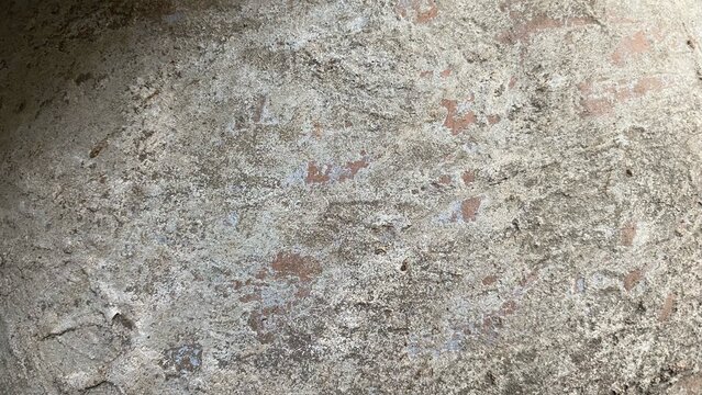 The rough, dull, and peeling surface texture of old concrete&mdash;featuring natural patterns and remnants of paint&mdash;serves well as an abstract background and a grunge material.