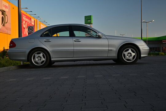 Silver Mercedes-Benz E-Class W211 E 220 CDI sedan parked outdoors, side view.