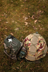 Obraz premium Tactical military helmet and medical IFAK pouch on ground