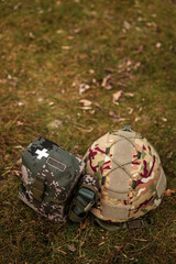 Obraz premium Tactical military helmet and medical IFAK pouch on ground