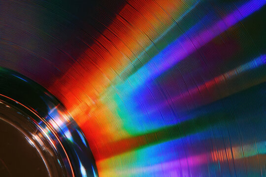 Close-up of CD or DVD disc surface showing rainbow light diffraction patterns and iridescent colors