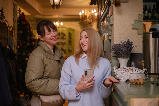 Two women enjoying a moment together in a cafe during wintertime with decorations