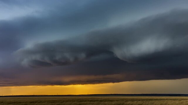 Dramatic storm clouds rolling over a wide plain in time-lapse with golden light