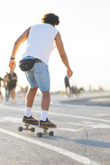 Skater moves along a busy path at sunset, enjoying a ride on a skateboard with others in the background © KONSTANTIN SHISHKIN