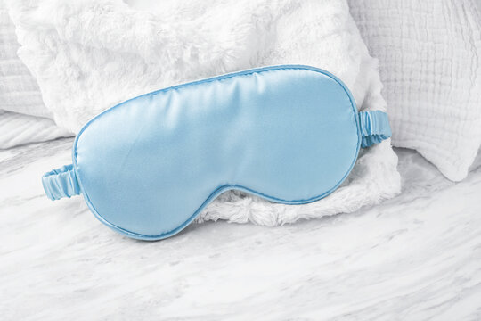 Silk sleeping mask on soft fabric on marble background