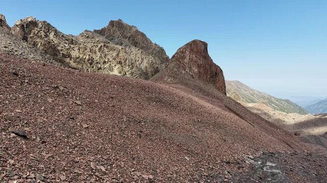 Cinematic drone flyover over rocky peaks, Oktyabrskaya cave, and shrinking ice blocks near Talgar Pass at 3400 meters altitude, revealing climate change and glacier melting in Tian Shan mountains near
