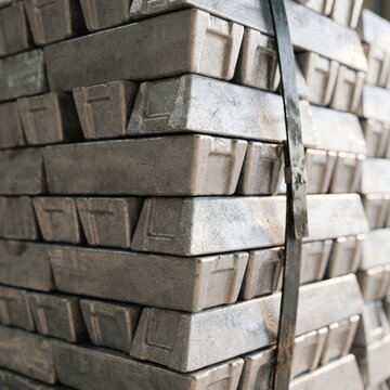 Stacks of rectangular metal ingots secured with steel strapping, close-up industrial raw material and metallurgy background