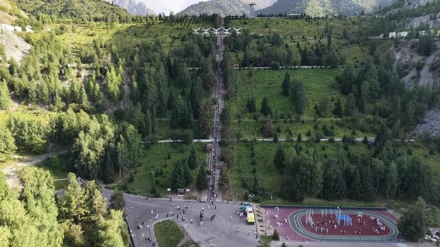 Cinematic drone flyover moving toward massive concrete stairways leading up to Medeu mudflow protection dam with outdoor sports facility at the base in Almaty, Kazakhstan at summer sunset.