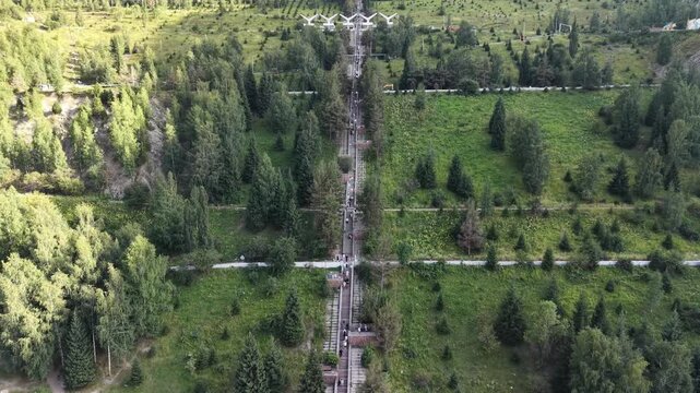 Cinematic drone flyover moving toward massive concrete stairways leading up to Medeu mudflow protection dam with outdoor sports facility at the base in Almaty, Kazakhstan at summer sunset.