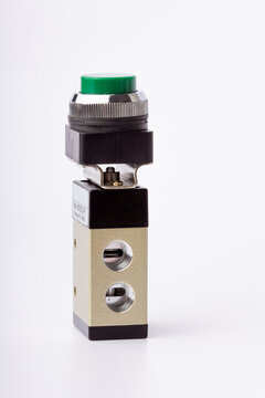 Studio shot of a 3/2-way mechanically actuated pneumatic valve with a green push-button switch and aluminum valve body, isolated on a clean white background. Detailed vertical view showing the mountin