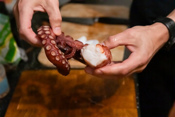 Hands holding sliced boiled octopus tentacle close up © Olesia Basova