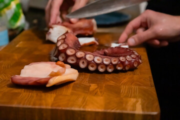 Hand with knife near boiled octopus tentacle on board © Olesia Basova